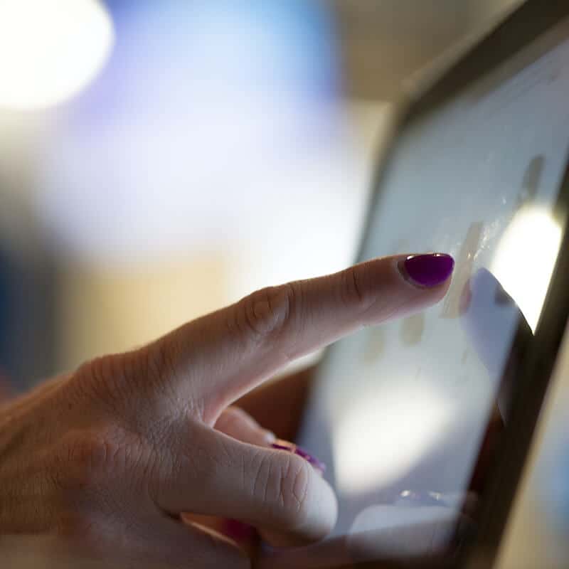 A close up image of a woman's hand scrolling through the options of mental health therapists in Central London using her personal touch screen device. The woman is trying to find a counsellor or psychotherapist in Angel or Farringdon, London. She is looking for personalised therapy with the best therapist who can help with Trauma and PTSD.