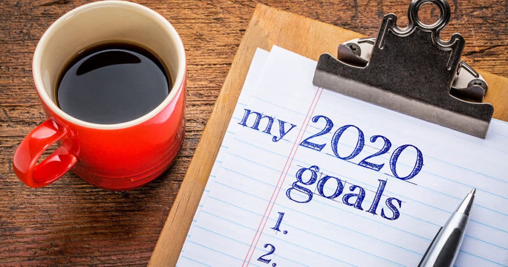My 2020 goals list on clipboard and coffee against grunge wood desk, New Year resolutions and new year goal setting can be a great time to focus on your personal and spiritual health and happiness. Professional, expert counseling at YTherapy in Central London can help!