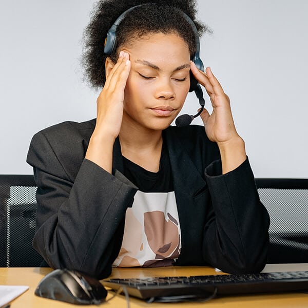 Woman wearing headset with her eyes closed appears anxious and overwhelmed. The woman is thinking about counselling to help her manage anxiety at work in the emergency services.