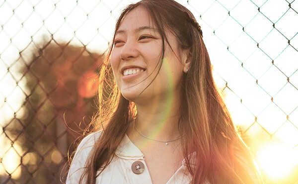Young woman smiling in the sunshine. Through counselling with YTherapy, the woman feels less stressed and more free to be herself.