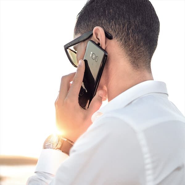 Man wearing glasses with head turned away is on the phone with a therapist. YTherapy offers a free consultation for individuals and organisations in need of therapy and wellness services.