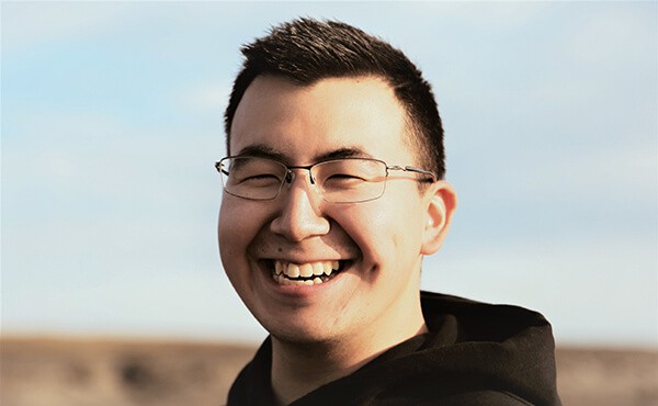 Man with glasses smiling at the beach. Since therapy, the man is feeling less anxious and more resilient, and now able to better manage his trauma and PTSD symptoms.