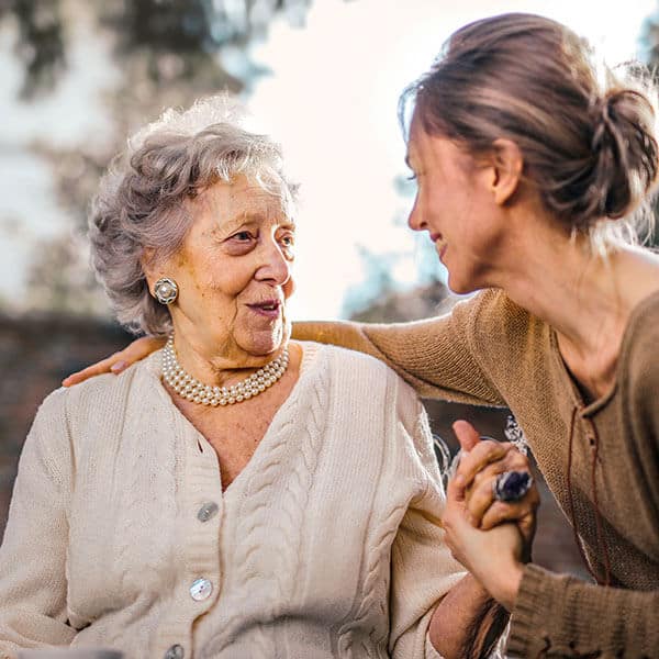 Young woman caring for an elderly woman. This professional caregiver is aware of workplace stress and burnout, and is looking after her own mental health and wellness when helping others.