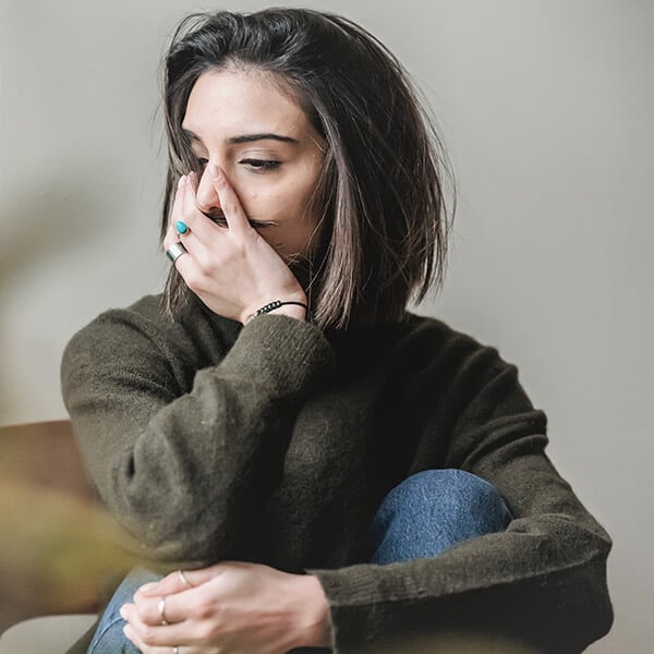 Woman with messy hair appears stressed and anxious. This therapist can treat trauma with her counselling clients but needs support for her ptsd symptoms.