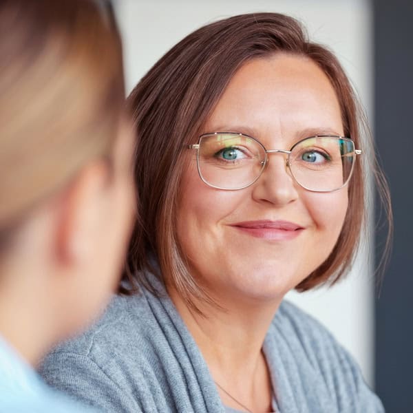 A smiling woman receiving support from an EAP Counsellor in a workplace setting, feeling happy and positive after a therapy session.